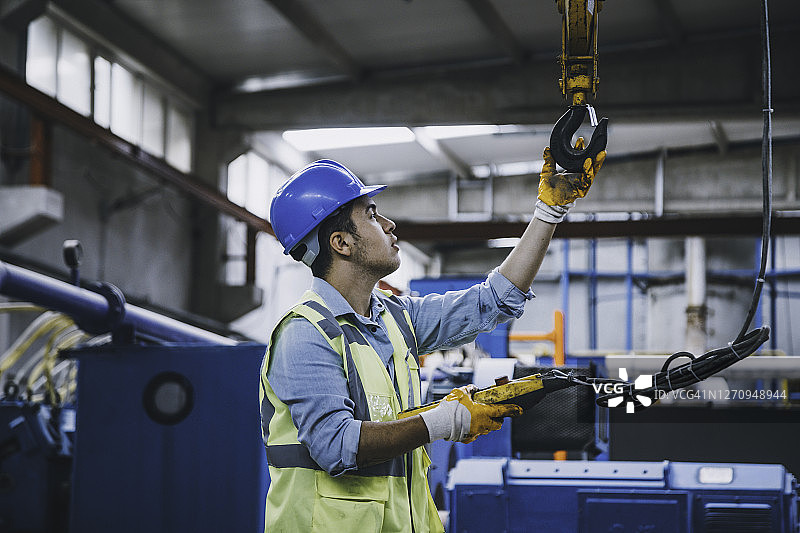 手持遥控器操作起重机的年轻商人图片素材