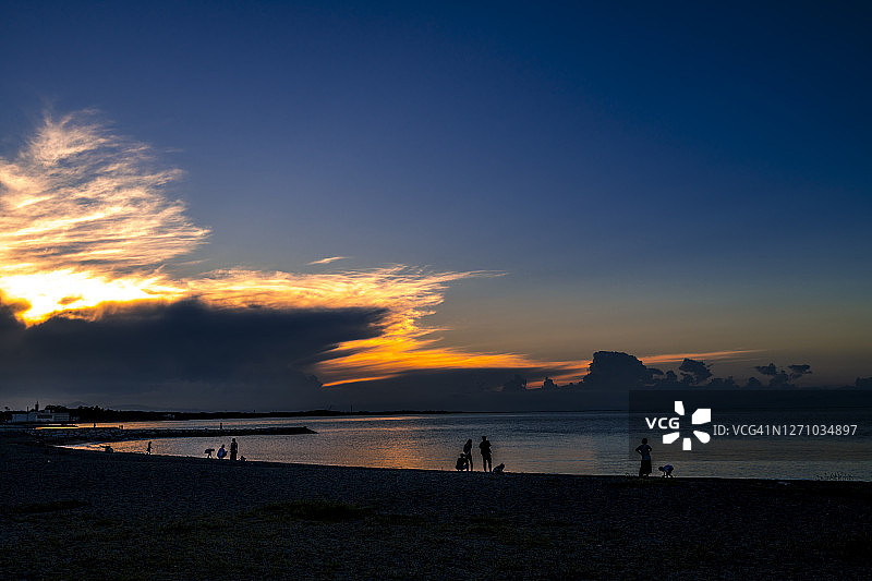 在海滩上漫步的人们，日落剪影图片素材