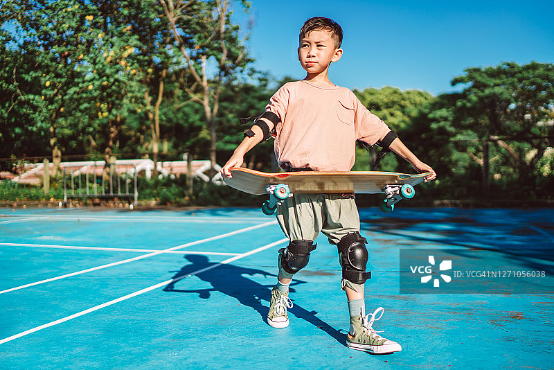 在阳光明媚的运动公园里玩滑板的小男孩图片素材
