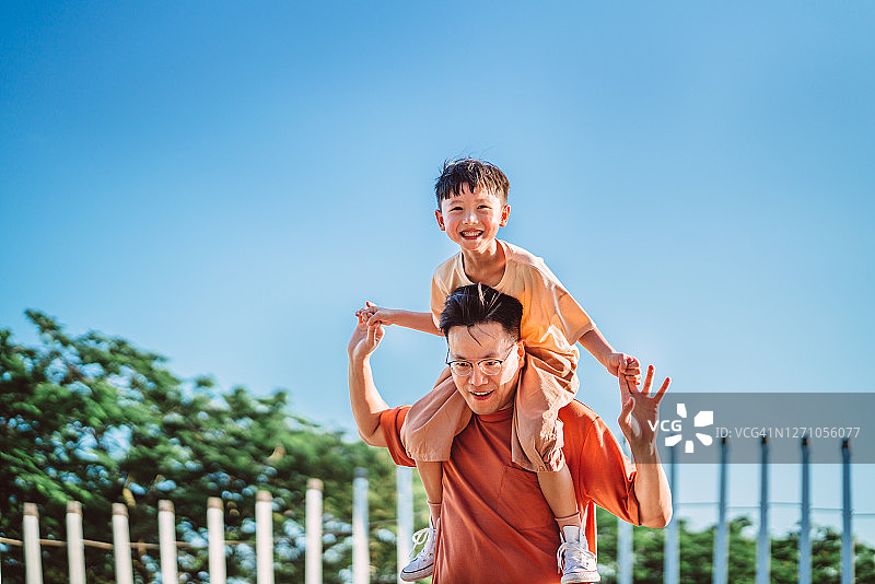 快乐的儿子高兴地骑在他爸爸的肩膀上图片素材
