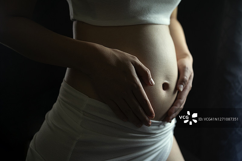 孕妇触摸腹部等待新生命降生的美丽特写图片素材