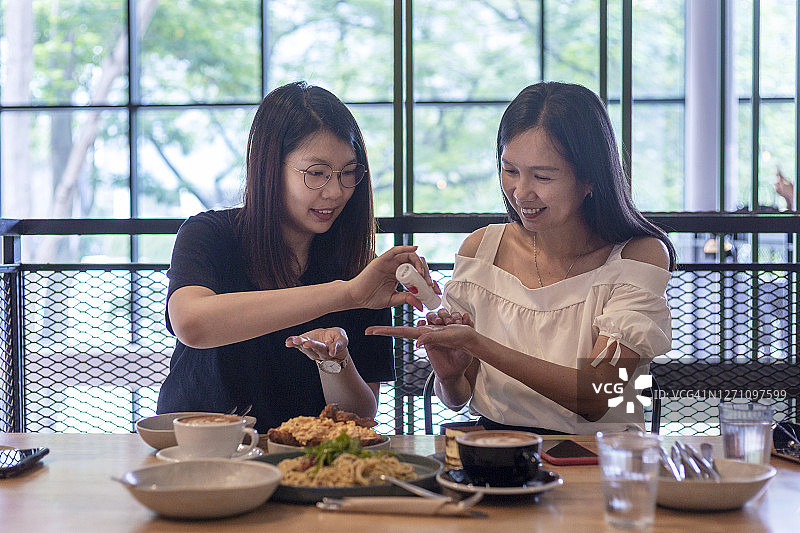 朋友们在咖啡馆使用消毒凝胶图片素材