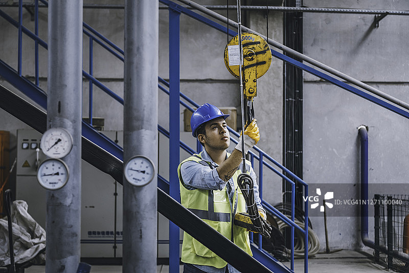 手持遥控器操作起重机的年轻商人图片素材
