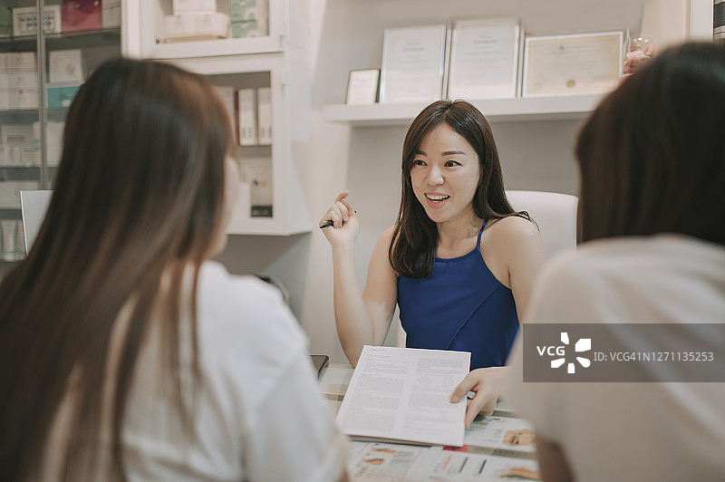 华裔美容师向顾客讲解美容套餐图片素材