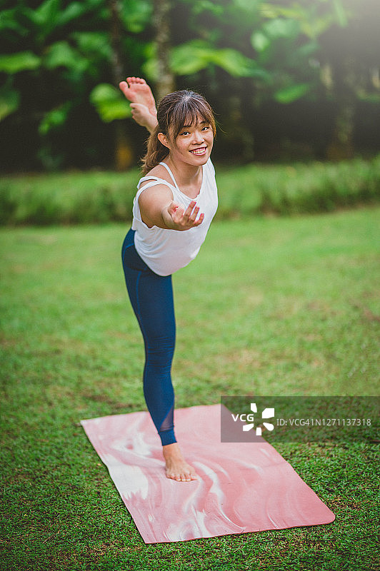 年轻漂亮的亚洲女性在公园练习瑜伽图片素材