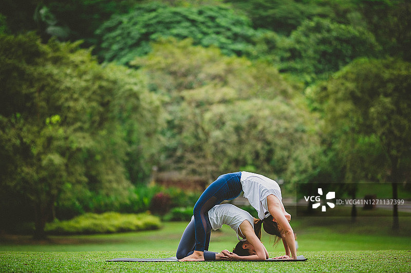 两名年轻的亚洲女性在户外练习双人瑜伽放松身心图片素材