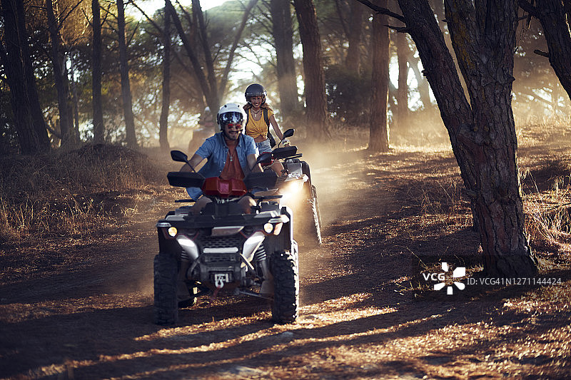 两位戴头盔的朋友在森林中骑沙滩车玩乐图片素材
