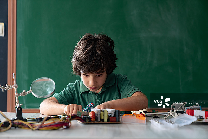 在绿色黑板前进行机器人和编程工作的小学生图片素材