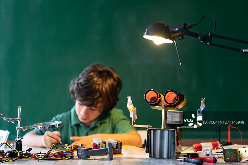 在绿色黑板前进行机器人和编程工作的小学生图片素材
