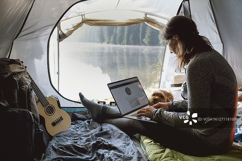 年轻女人在帐篷里用笔记本电脑工作图片素材
