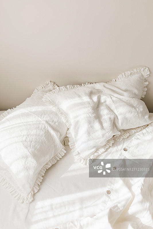 阳光明媚的早晨，褶皱枕头的白色亚麻床上用品图片素材