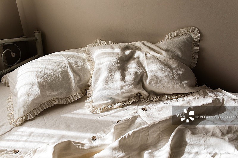 阳光明媚的早晨，褶皱枕头的白色亚麻床上用品图片素材