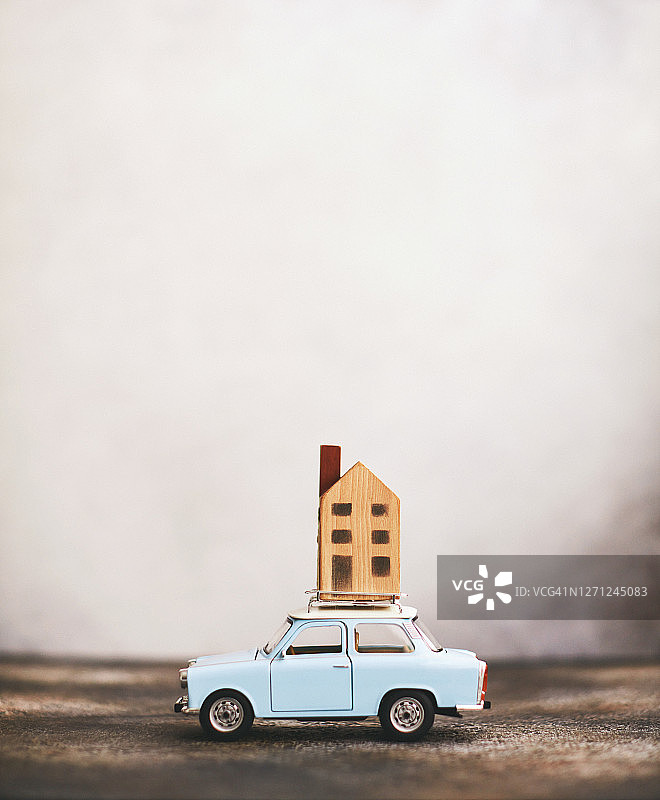 车顶载着房屋的蓝色小汽车，搬迁概念图片素材