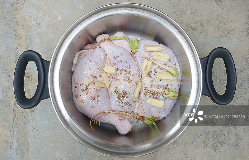 不锈钢锅中的生鸡腿和调味料图片素材