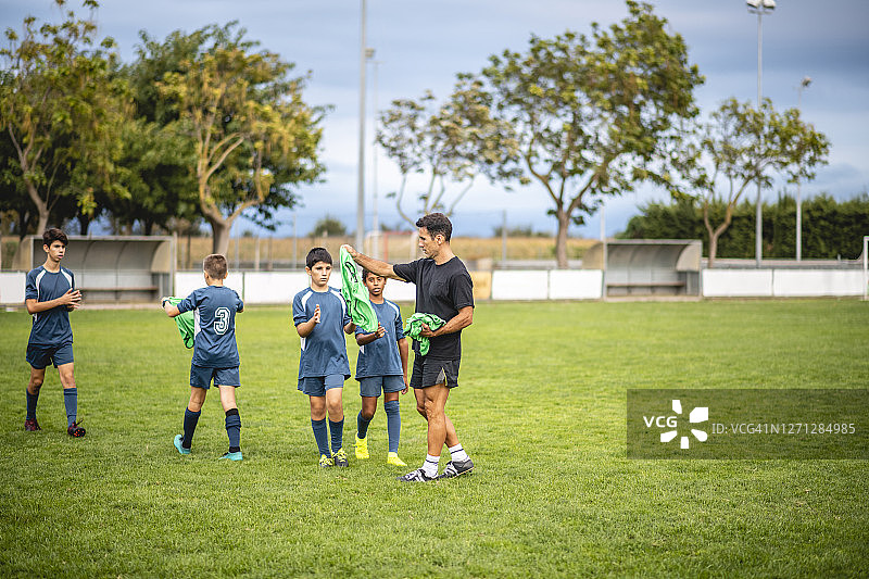 教练给青少年足球运动员分发训练背心图片素材