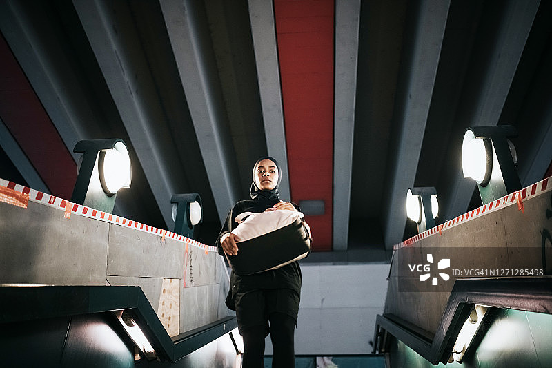 戴着运动头巾的年轻运动女性走下柏林地铁站的混凝土楼梯图片素材