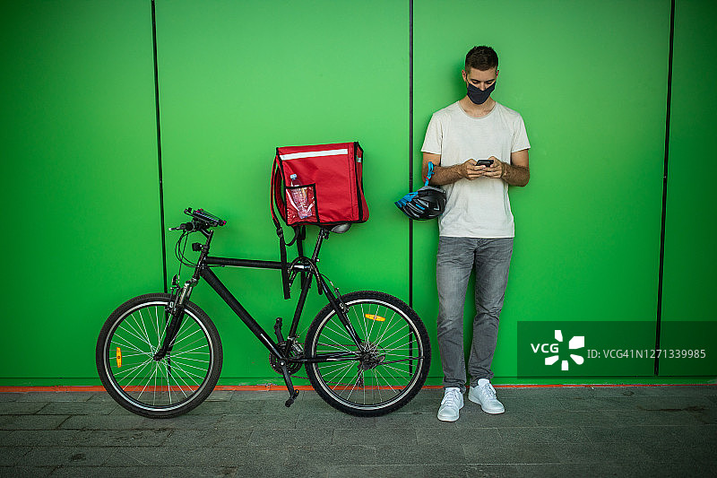 戴防护口罩，用手机定位下一个客户的送货员图片素材