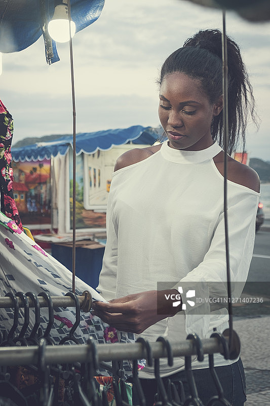 一位三十多岁的拉丁美洲黑人妇女在街头市场看衣服图片素材