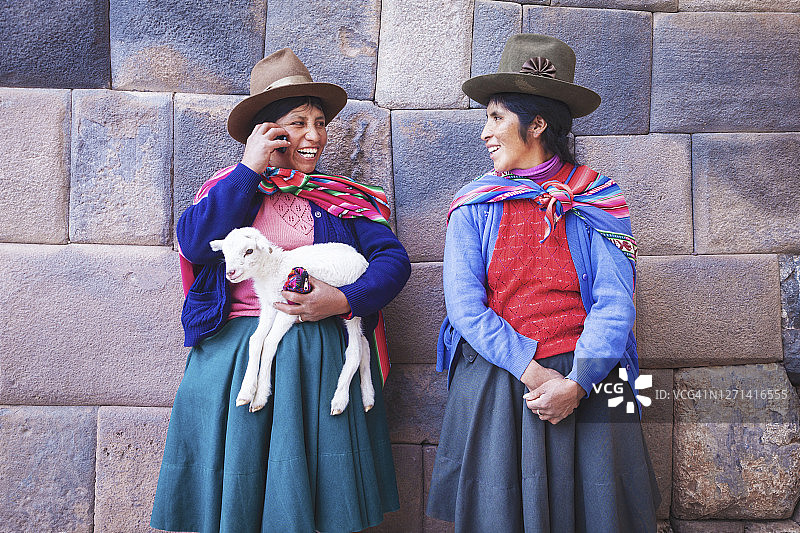 库斯科的秘鲁土著妇女，一人正在使用手机图片素材