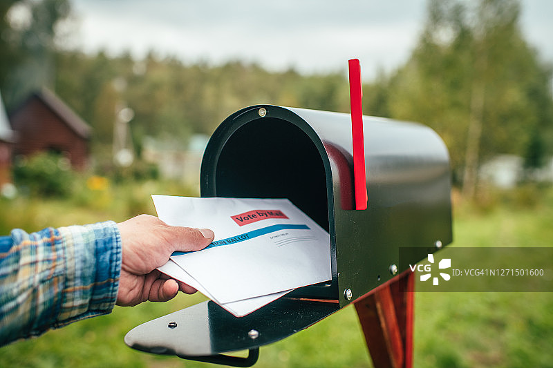 男子在邮箱旁用手寄送或接收选票信件的特写镜头图片素材