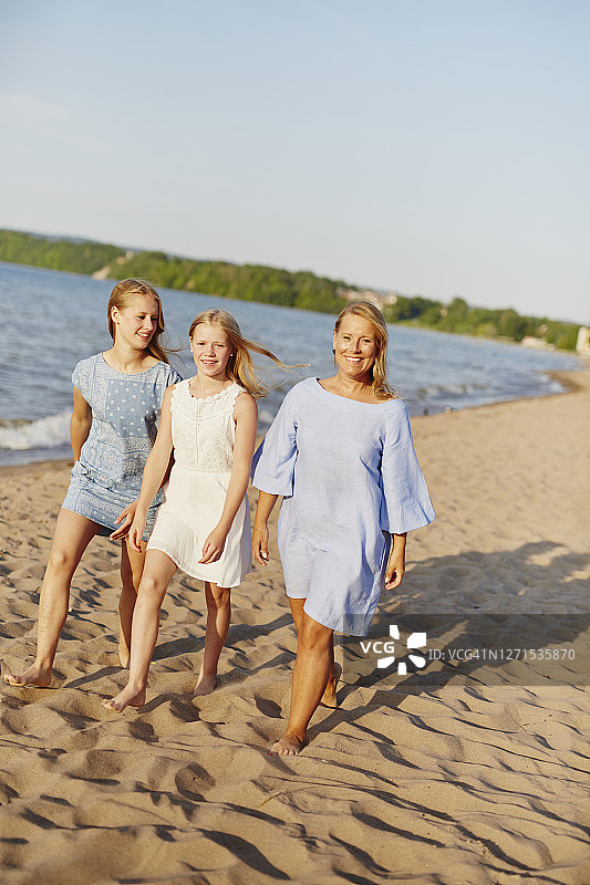 母亲和女儿们在沙滩上散步图片素材