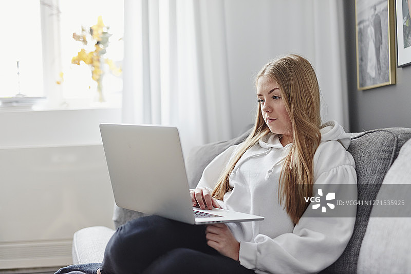 在沙发上使用笔记本电脑的女人图片素材