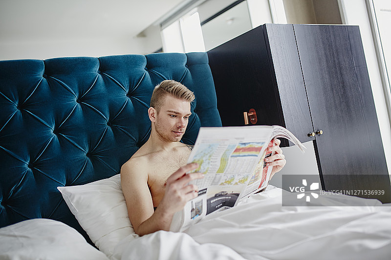 男人在床上阅读报纸图片素材
