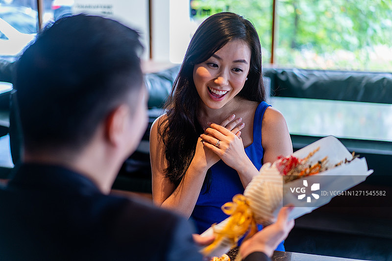 快乐微笑的亚洲女人收到男友送的鲜花。图片素材