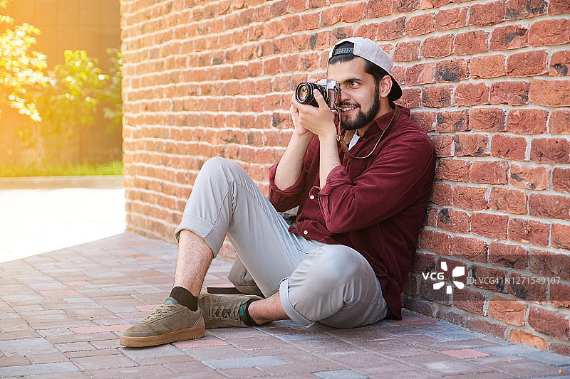 在户外工作的快乐的印度年轻男摄影师图片素材