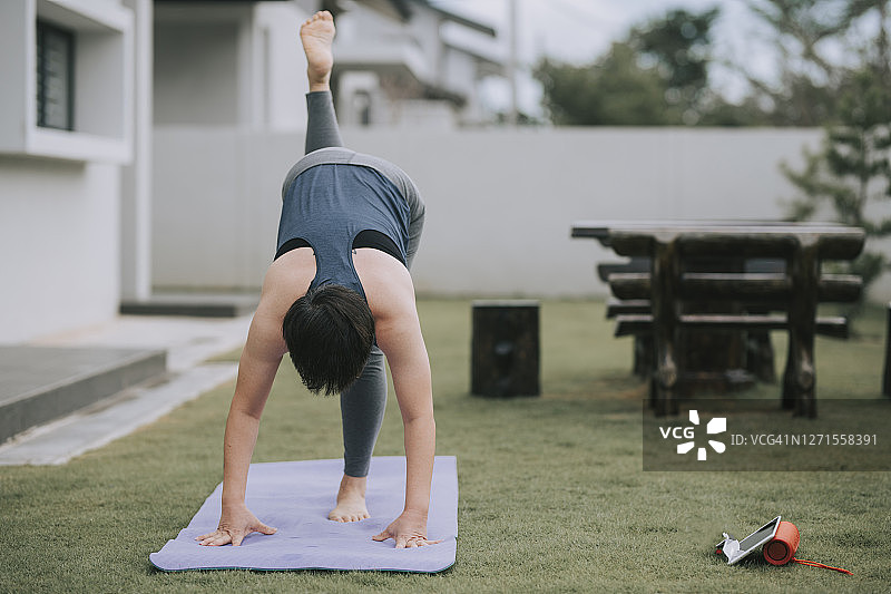 中国中年女性在房子前院练习瑜伽图片素材