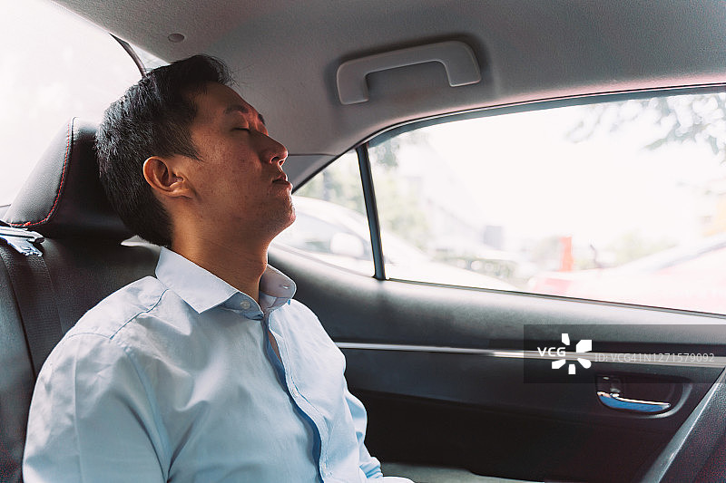 在汽车后座睡着的中年商人图片素材