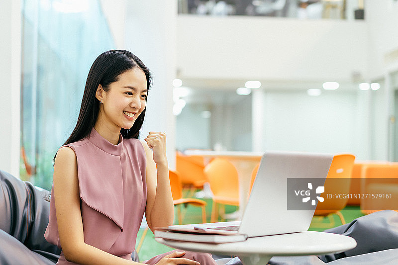 快乐成功的亚洲女商人使用笔记本电脑庆祝图片素材