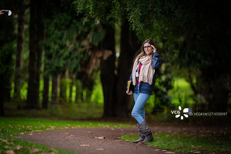穿蓝色球衣和蓝色牛仔裤在公园里看书的女人图片素材