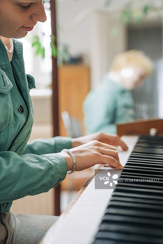 在家练习钢琴的年轻时尚女性图片素材