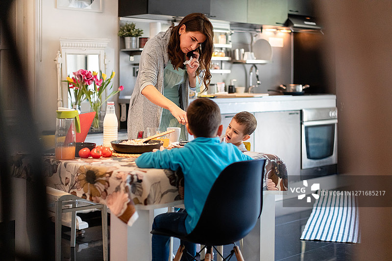 母亲打电话并为儿子们准备饭菜图片素材