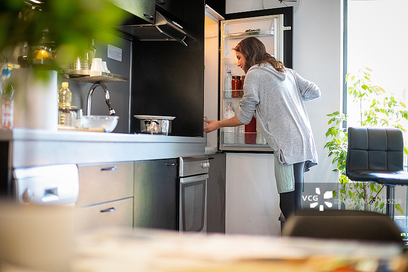 女人打开冰箱寻找午餐食材图片素材
