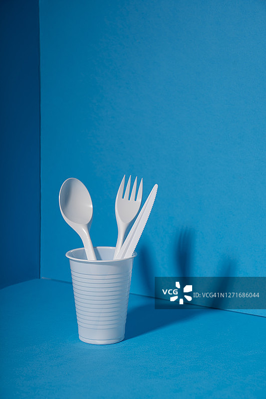一次性塑料餐具：环境问题与环境污染，蓝色背景图片素材