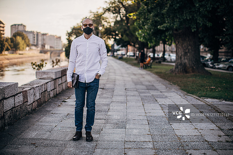 戴防护面罩站在城市街道上的年轻商人图片素材