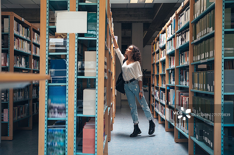 年轻学生在书架上选择书籍图片素材