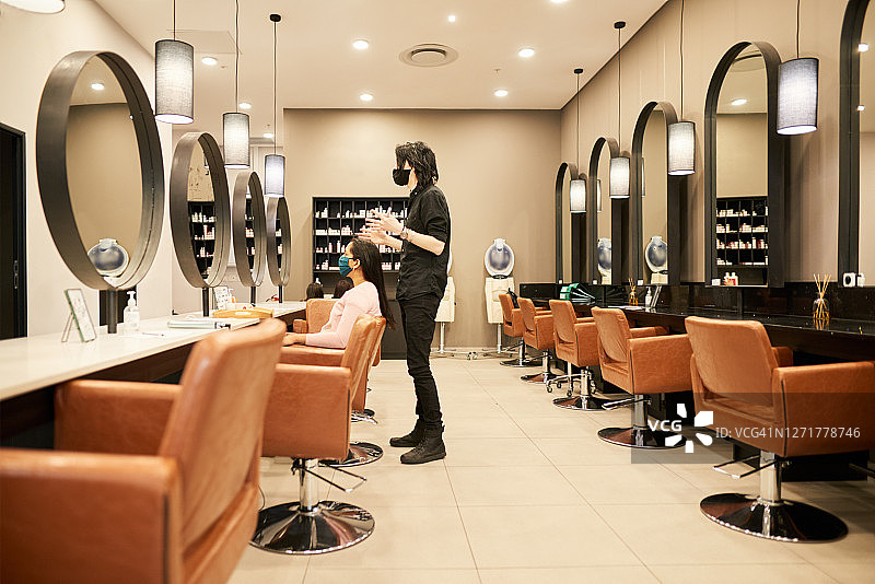戴口罩的发型师与沙龙顾客交谈图片素材
