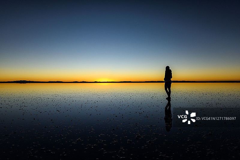 玻利维亚高原乌尤尼盐沼日落时分的男子剪影图片素材