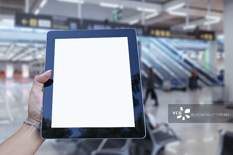 机场背景上手持平板电脑特写样机。航空旅行主题概念。图片素材