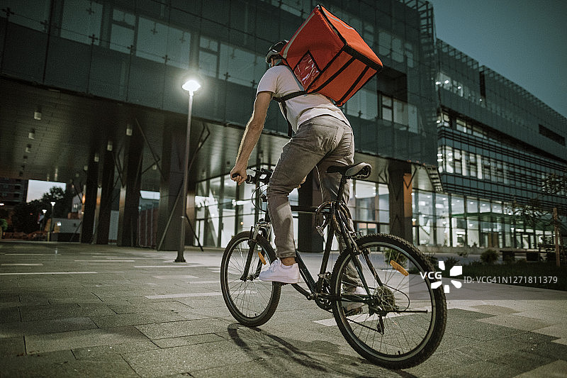 夜晚在城市中骑自行车送餐图片素材