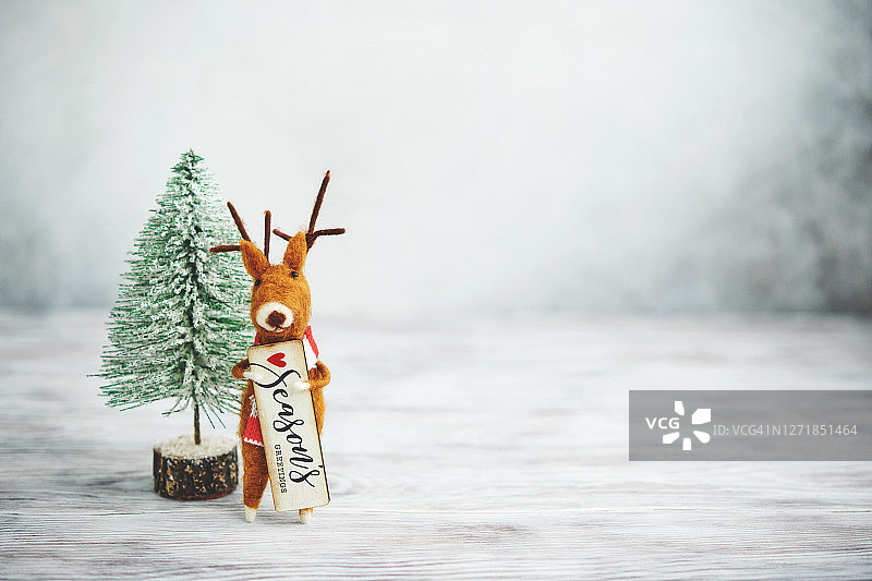 明亮的圣诞节背景与圣诞树和可爱的毛毡驯鹿图片素材