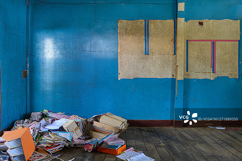蓝色墙壁，地板上堆满旧文具的废弃教室图片素材