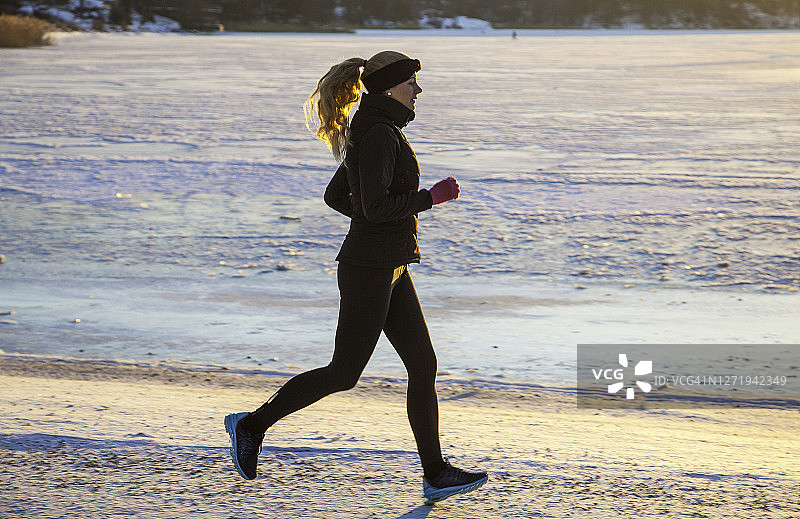 瑞典索伦蒂纳：冬季结冰水边锻炼慢跑的女人图片素材