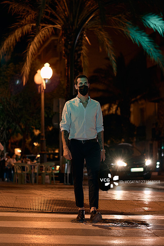 晚上戴着口罩走在街上的年轻商人图片素材