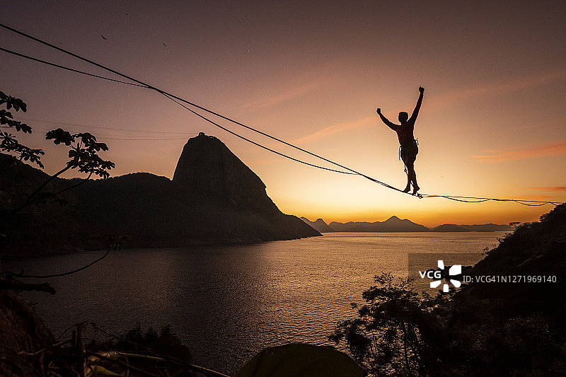日出美景：男子在高空绳索上行走，背景是面包山图片素材