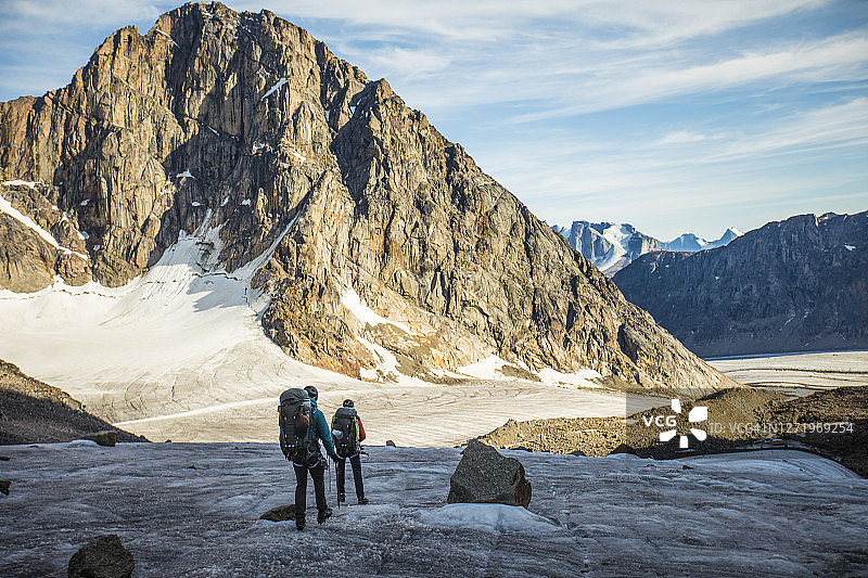 两名背包客穿越山脉下的冰川图片素材