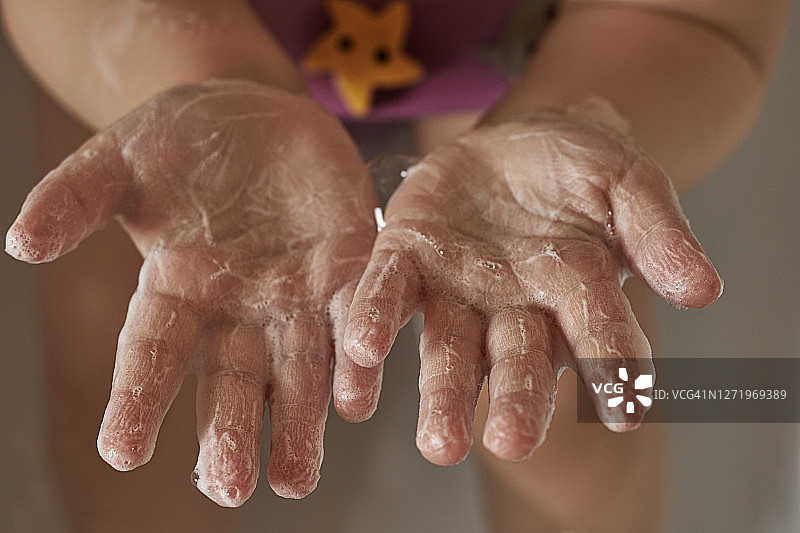 孩子的手在肥皂泡沫。手部卫生概念，大流行预防图片素材